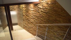 A staircase with a stone wall on one side and a glass railing on the other. - South Coast Hotels Thane (Thane)