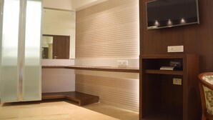 A modern bathroom with a large mirror, wooden vanity, and a mounted TV. - South Coast Hotels Thane (Thane)