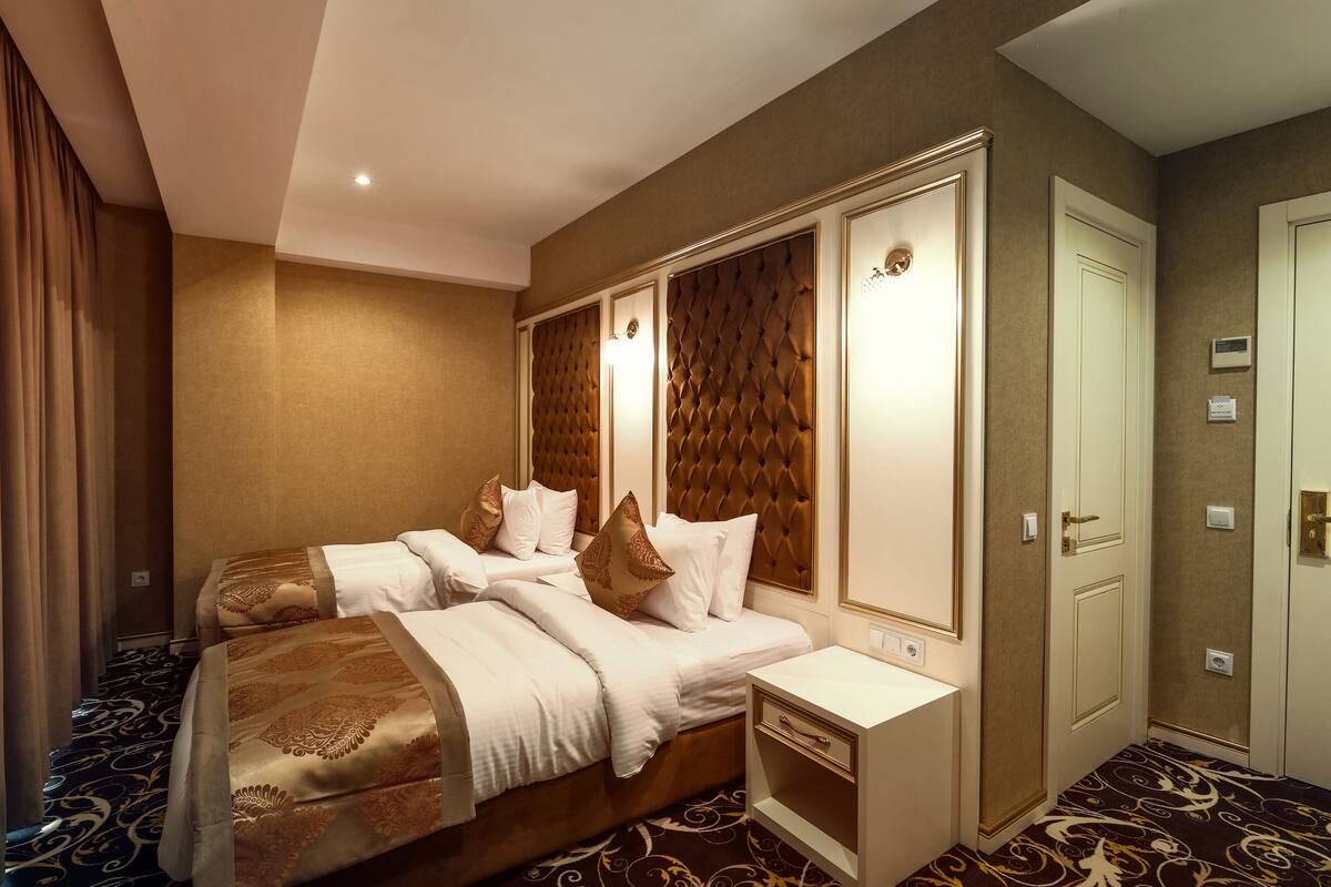 Ein Hotelzimmer mit einem großen Bett, einem Nachttisch, einem Kleiderschrank und einem Teppichboden.
