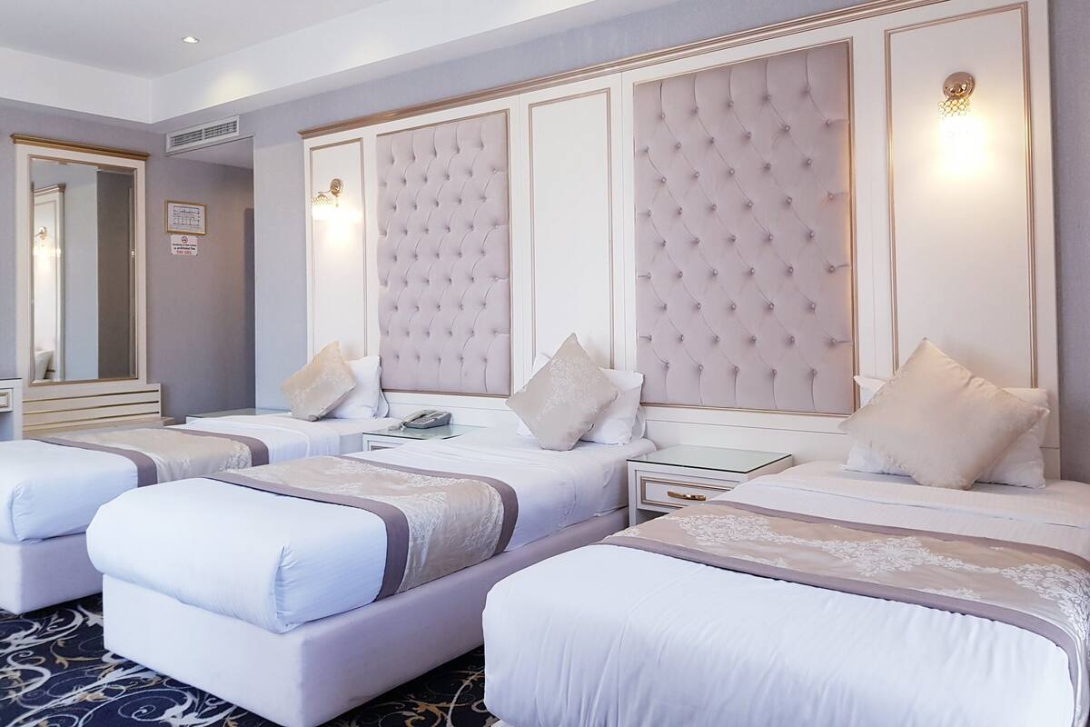 Ein Hotelzimmer mit zwei Betten, einem großen Spiegel und einem Nachttisch mit einer Lampe.