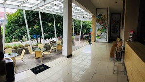 A spacious lobby with a glass ceiling, a reception desk, and a 'Welcome' mat. - Amaia Hotel (Mataram)