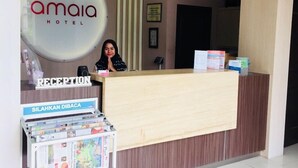 A reception desk with a sign reading "amaia hotel" and a clock on the wall. - Amaia Hotel (Mataram)