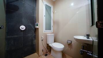 Et lille badeværelse med toilet, håndvask og brusebad.