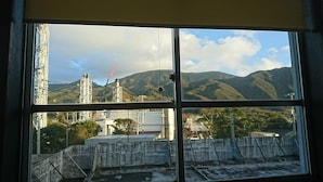 A window view of a mountainous landscape with industrial structures and a construction crane.