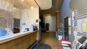 A reception area with a counter, a coffee machine, a telephone, and a bulletin board with papers.