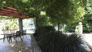 An outdoor patio area with a covered seating area and a tiled floor. - Country Apartments (Dubbo)