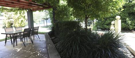 Un patio al aire libre con una zona de estar cubierta y suelo de baldosas.