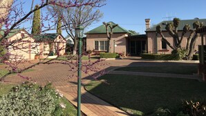 A residential area with a brick house, a green roof, and a well-maintained lawn. - Country Apartments (Dubbo)