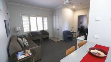 A living room with a sofa, armchairs, a coffee table, and a dining area with a table and chairs.
