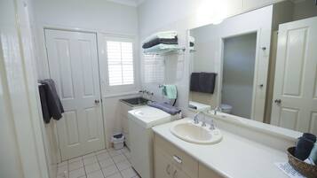 A bathroom with a sink, mirror, and two doors.