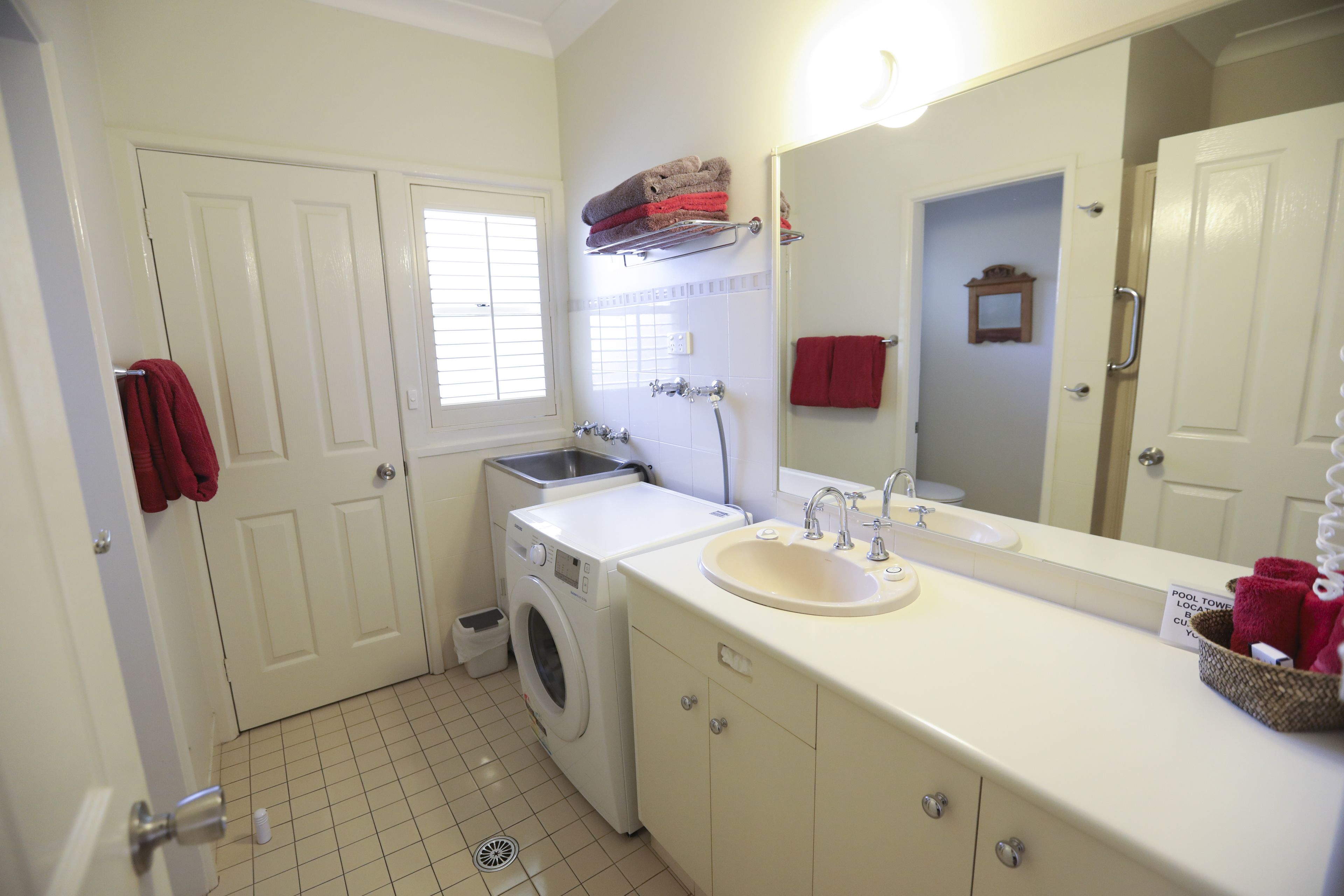 A bathroom with a washing machine, sink, and a mirror.