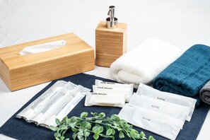 A wooden box, a tissue box, a towel, a blue towel, a razor, and hairbrushes on a table.