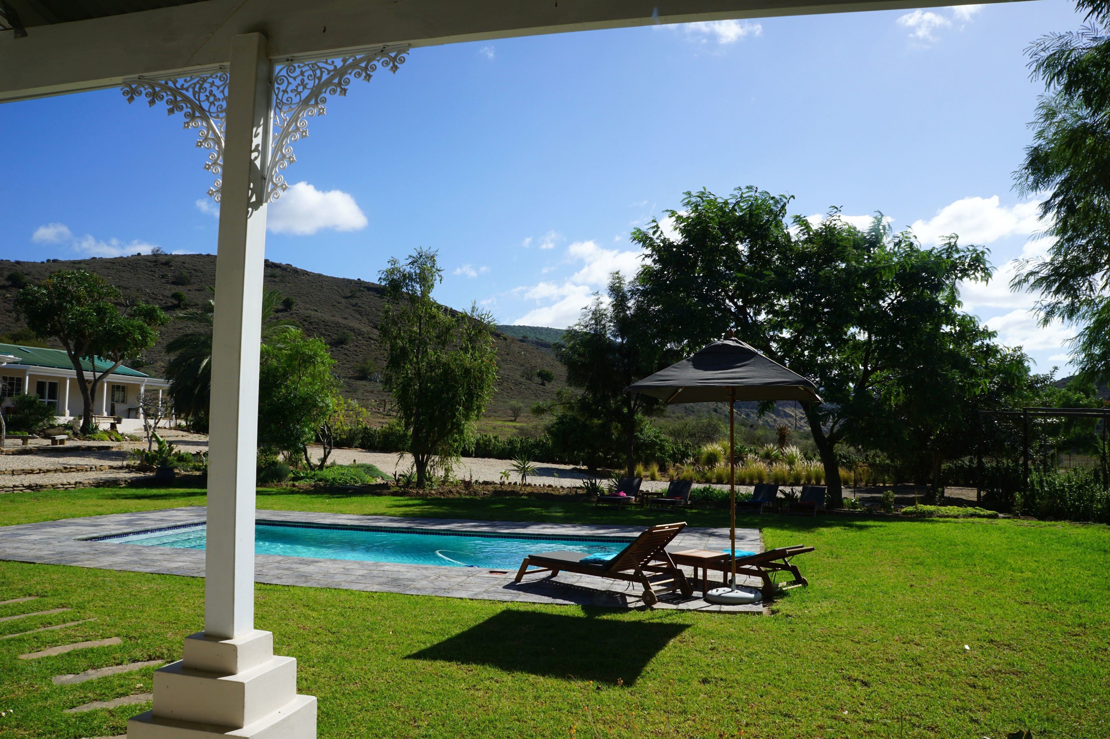Una piscina al aire libre, sombrillas, sillones reclinables de piscina