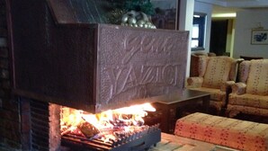 A brick fireplace with a decorative plaque, a Christmas tree, and a lit fire. - Genc Yazici Hotel Uludag (Bursa)