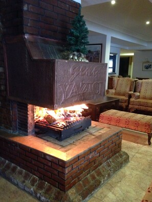 Una chimenea de ladrillo con una placa decorativa, un árbol de Navidad y fuego encendido.