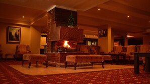 A cozy lounge area with a brick fireplace, comfortable seating, and a patterned carpet. - Genc Yazici Hotel Uludag (Bursa)