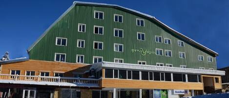A multi-story building with a green facade and multiple windows.