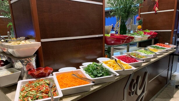 A buffet with various food items in white trays, including salads, vegetables, and fruits. - Genc Yazici Hotel Uludag (Bursa)