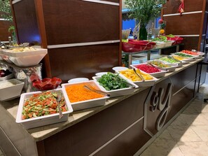 A buffet with various food items in white trays, including salads, vegetables, and fruits. - Genc Yazici Hotel Uludag (Bursa)