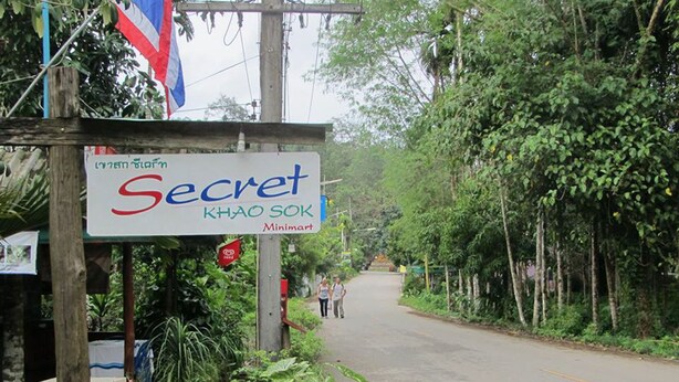Ein Schild für 'Secret Khao Sok' mit einem Minimart-Geschäft.