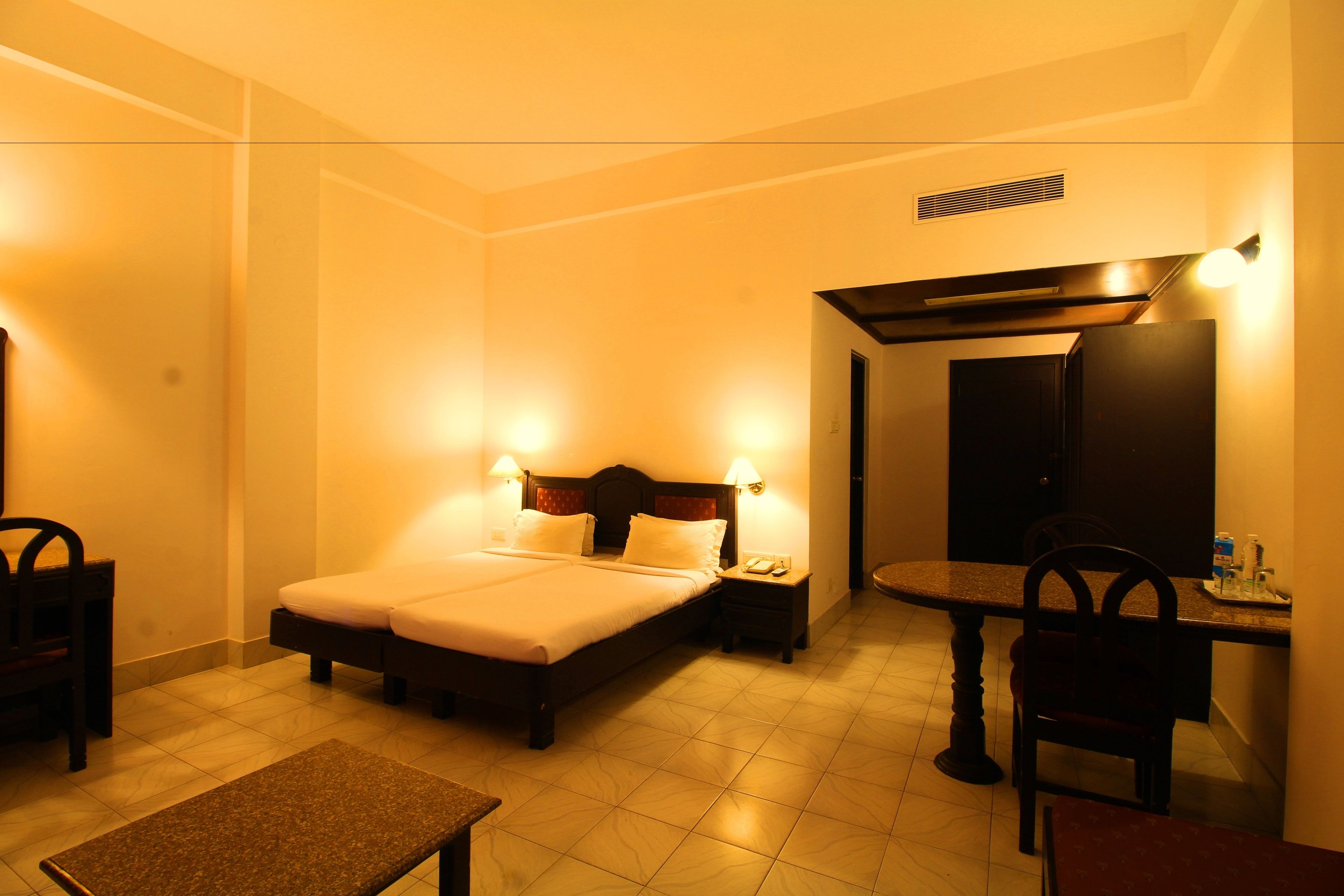 A hotel room with a bed, bedside tables, a desk, and a chair.