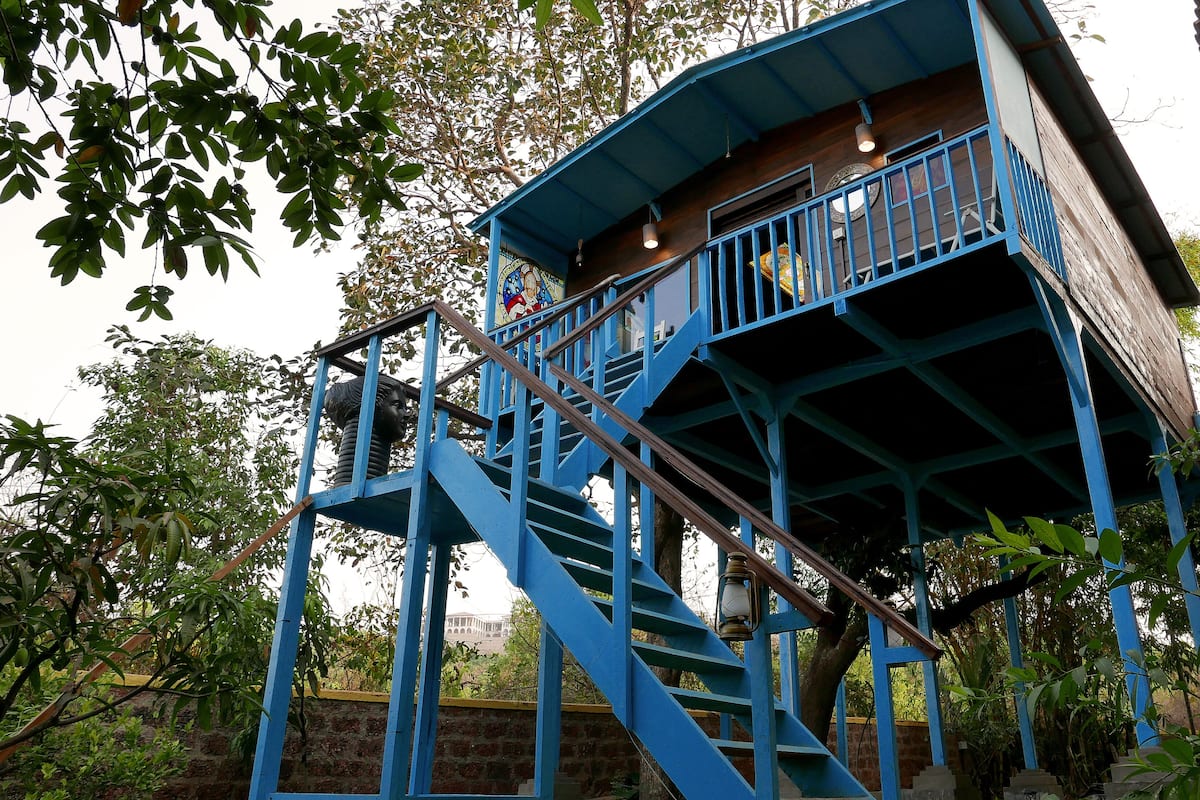 A blue wooden structure with a staircase leading to a balcony.