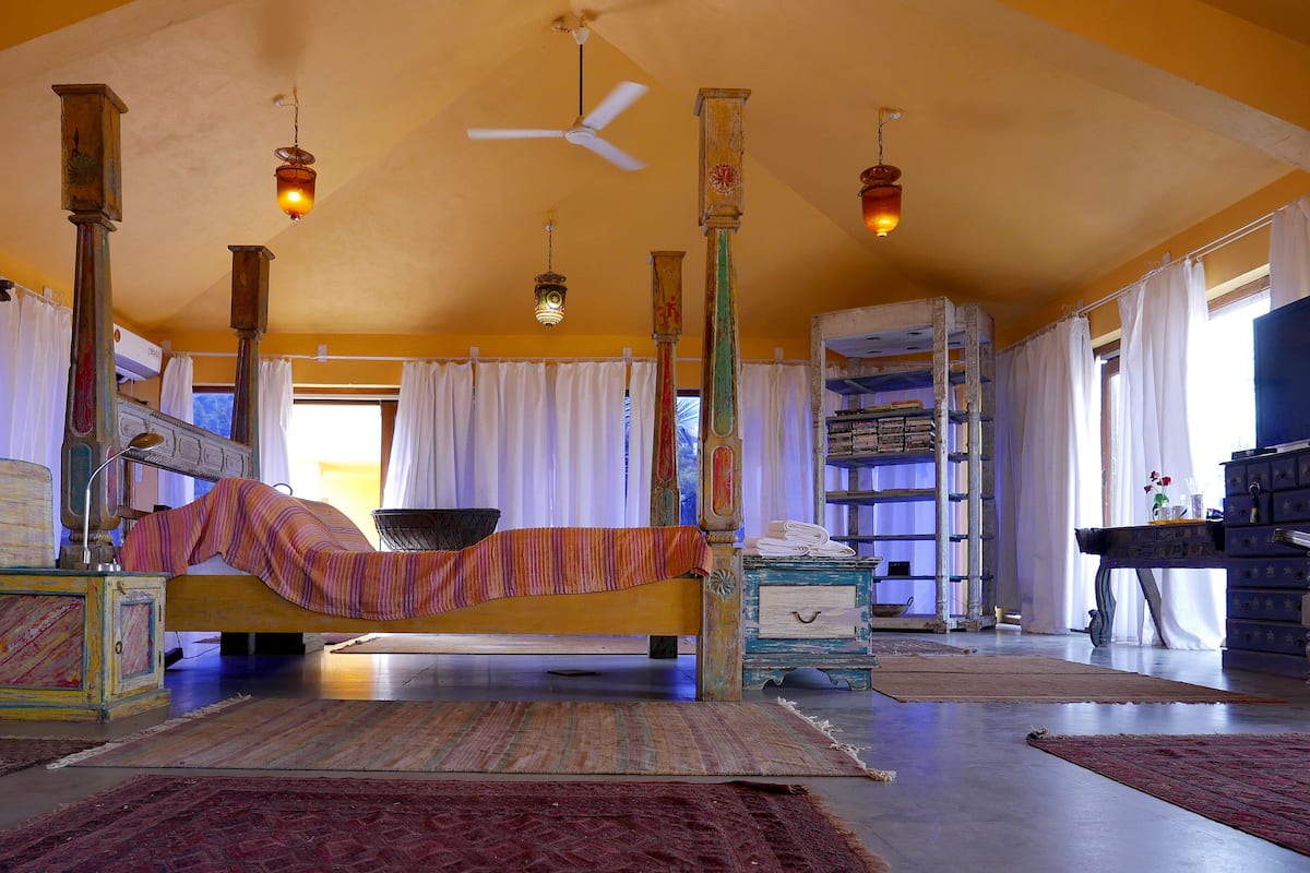 A spacious room with a large bed, a ceiling fan, and a bookshelf.