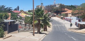 A residential street with houses, palm trees, and a clear sky.
