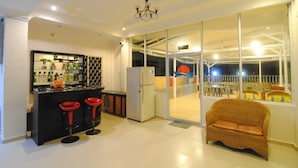 A modern kitchen with a bar area, a wicker sofa, and a glass door leading to an outdoor patio.