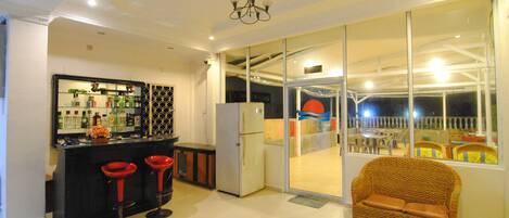 A modern kitchen with a bar area, a wicker sofa, and a glass door leading to an outdoor patio.