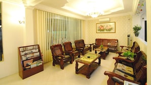 A traditional living room with wooden furniture, a bookshelf, and a chandelier.