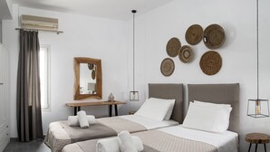 Una habitación de hotel moderna con dos camas, un cabecero de madera, un espejo y decoraciones tejidas en la pared.