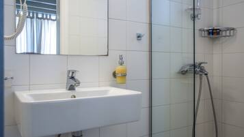 Une salle de bain avec un lavabo blanc, un miroir et une douche.