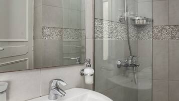 Een moderne badkamer met een wit wastafelmeubel, een douchecabine van glas en een spiegel boven het wastafelmeubel.