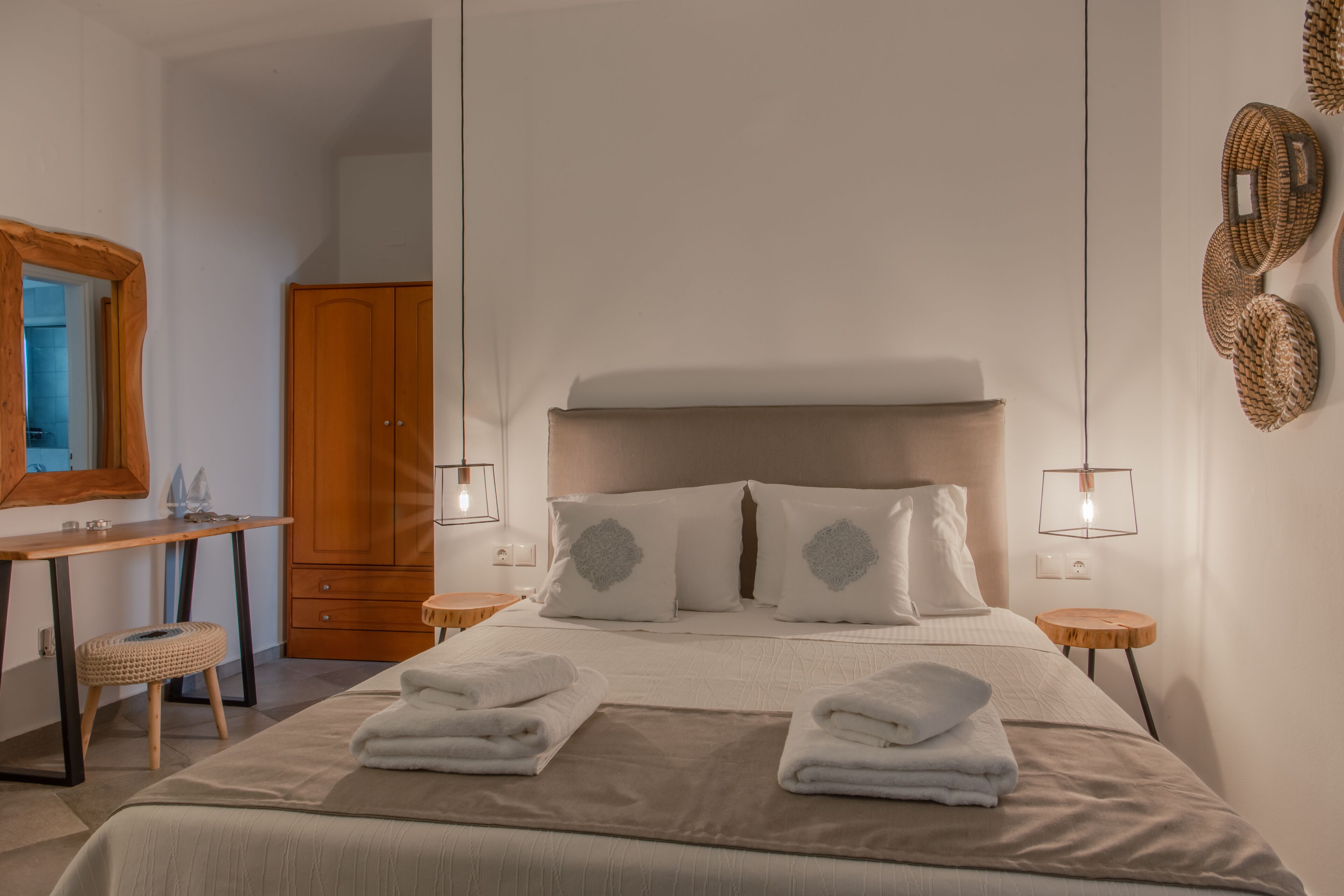 A hotel room with a bed, bedside tables, a desk, a wardrobe, and a mirror.