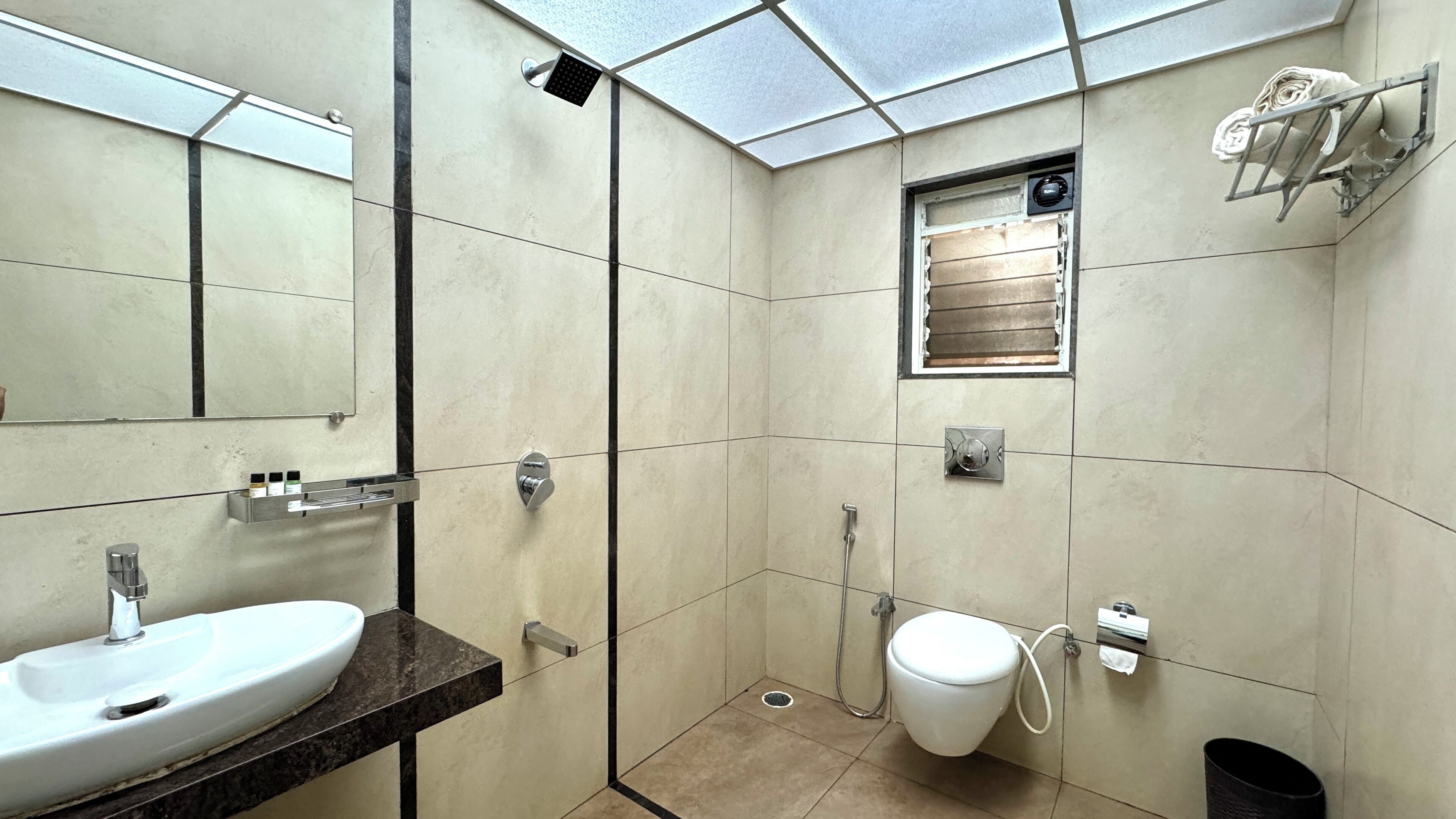 Un baño moderno con un espejo grande, un lavamanos, una ducha y un inodoro.