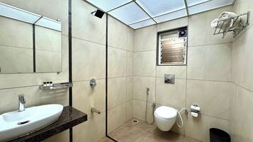 Un baño moderno con un espejo grande, un lavamanos, una ducha y un inodoro.