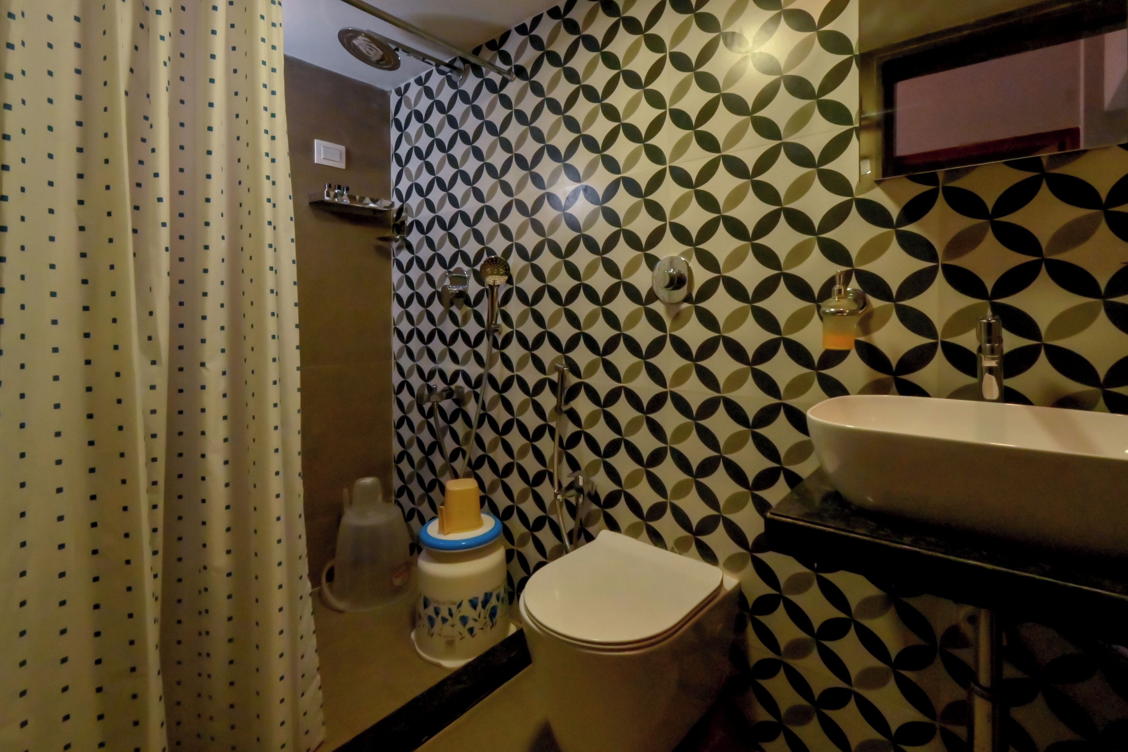 A bathroom with a patterned wall, a toilet, a sink, and a shower curtain.