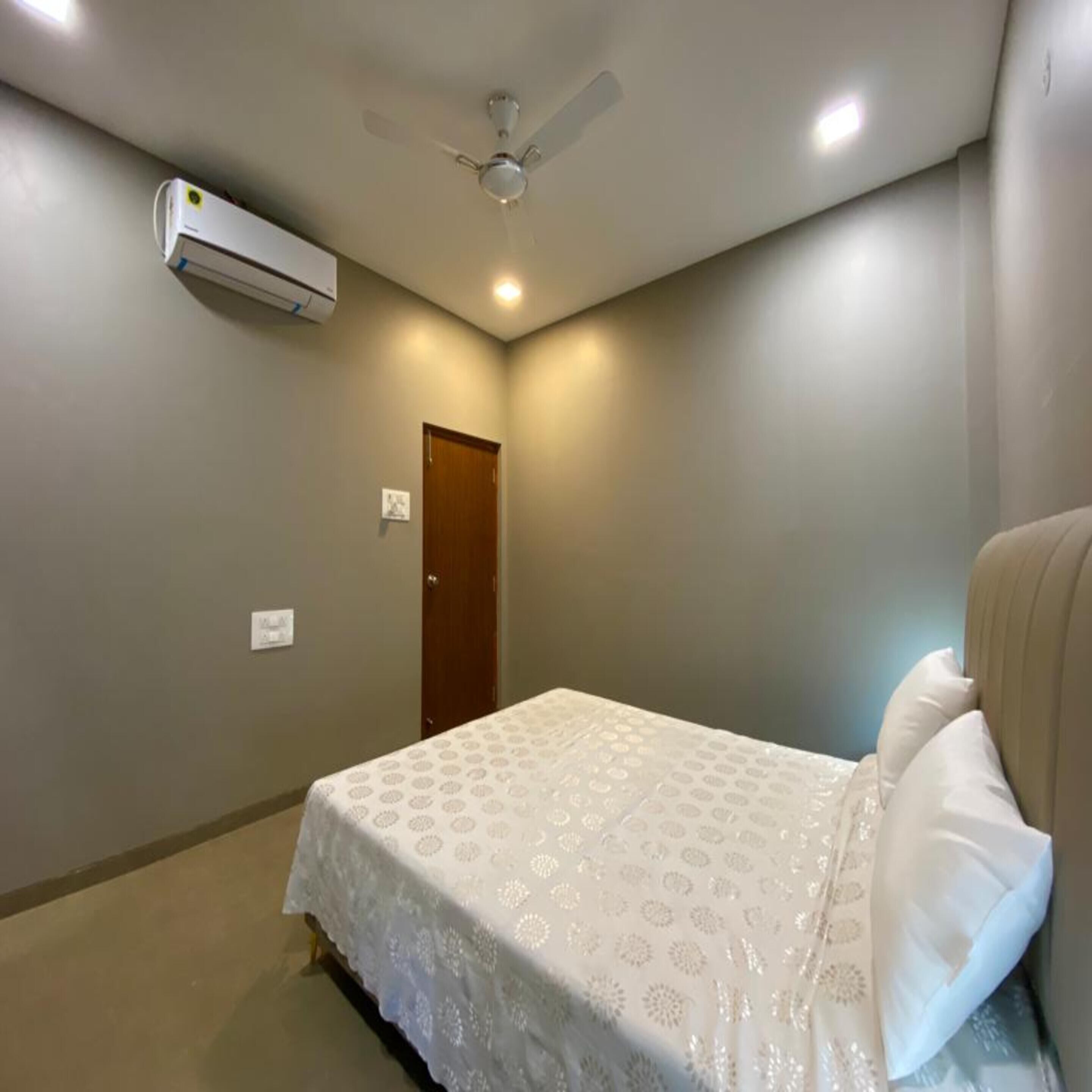 A bedroom with a bed, a ceiling fan, and an air conditioning unit.