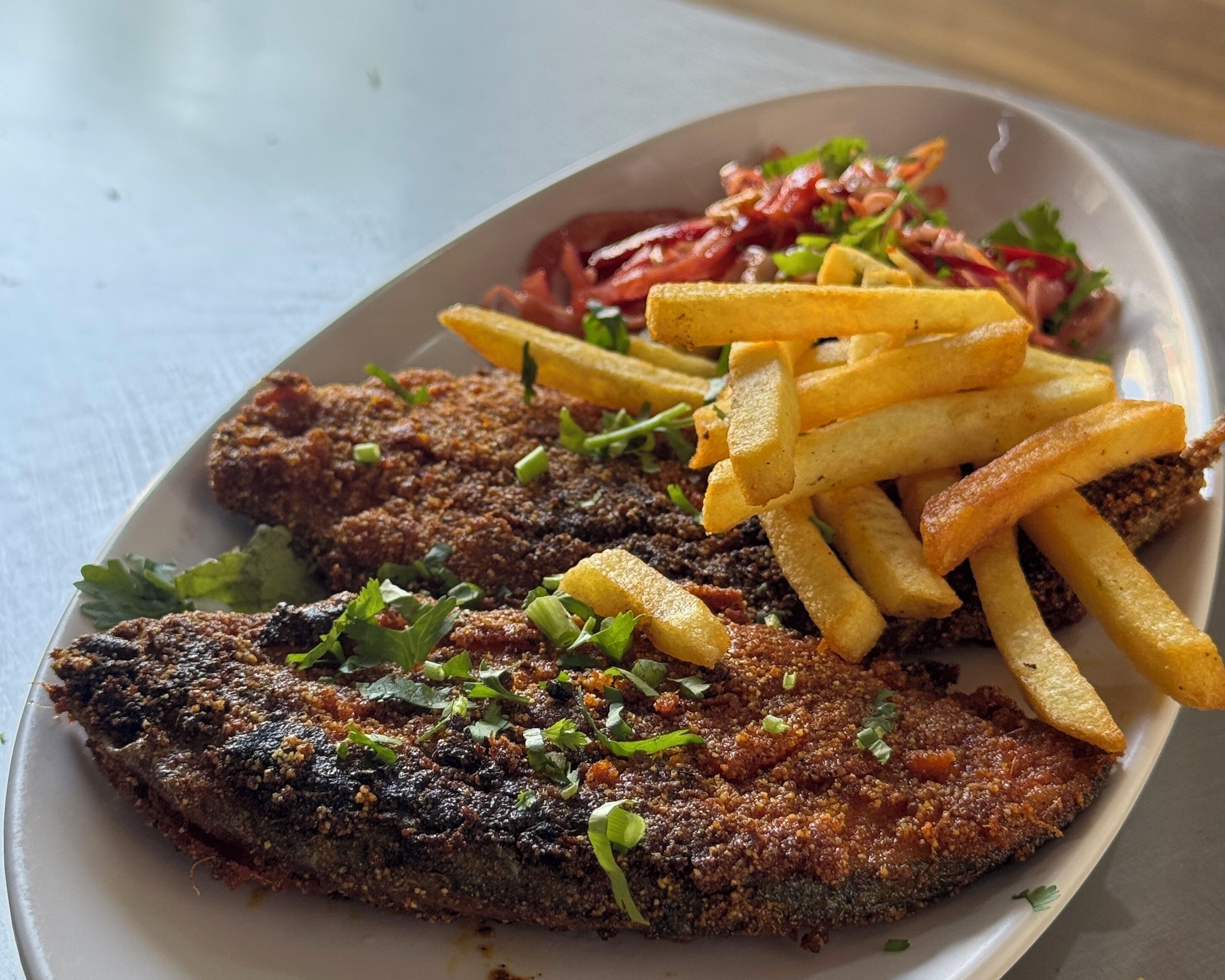 Une assiette avec deux filets de poisson panés, une portion de frites et une salade.