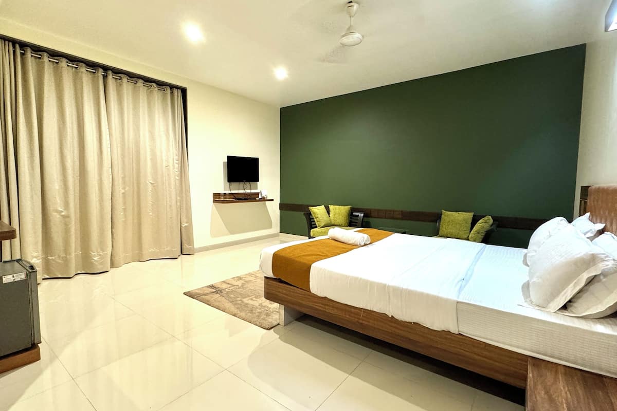 A hotel room with a bed, a desk, a television, and a window with curtains.