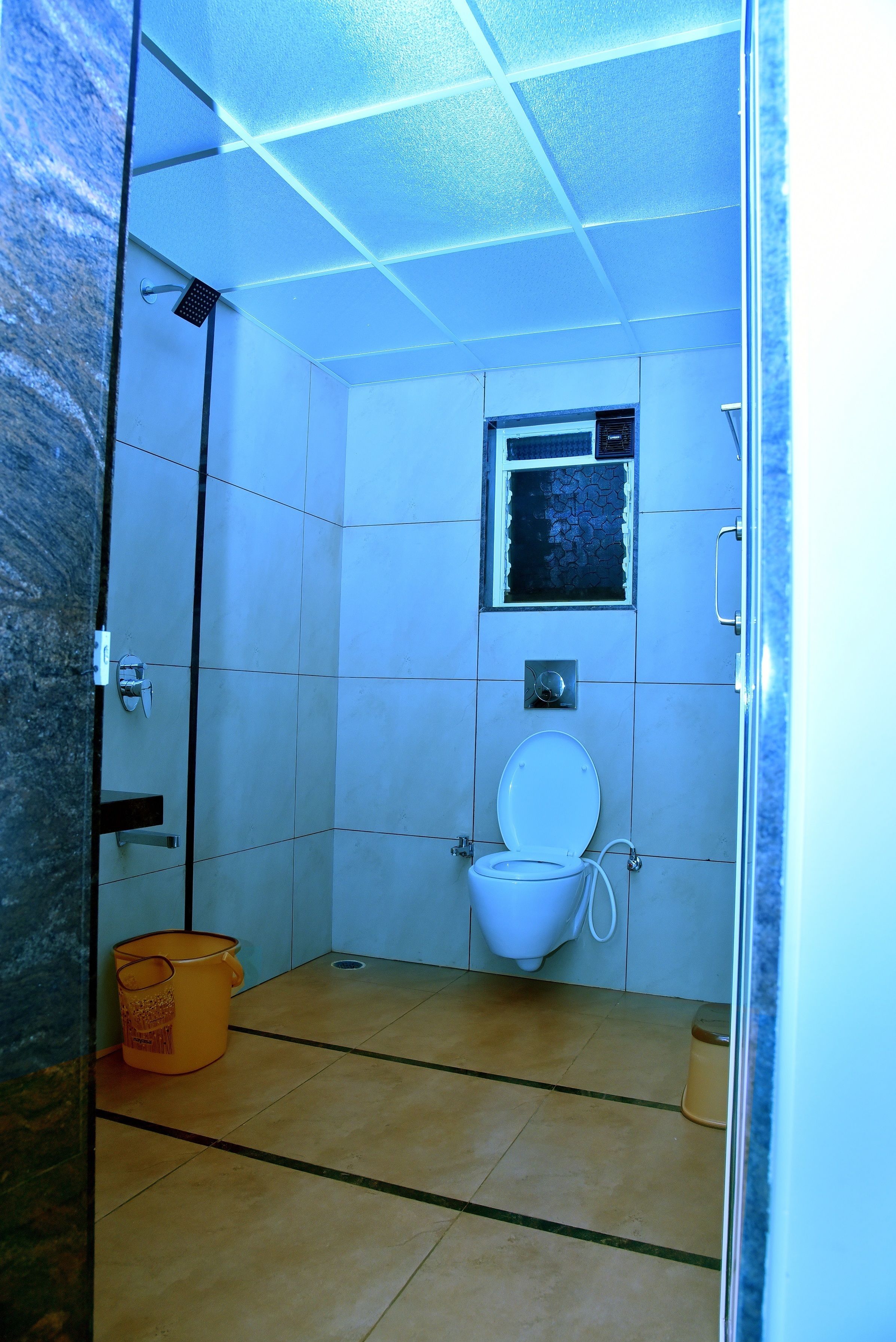 A small, tiled bathroom with a toilet, a shower, and a window.