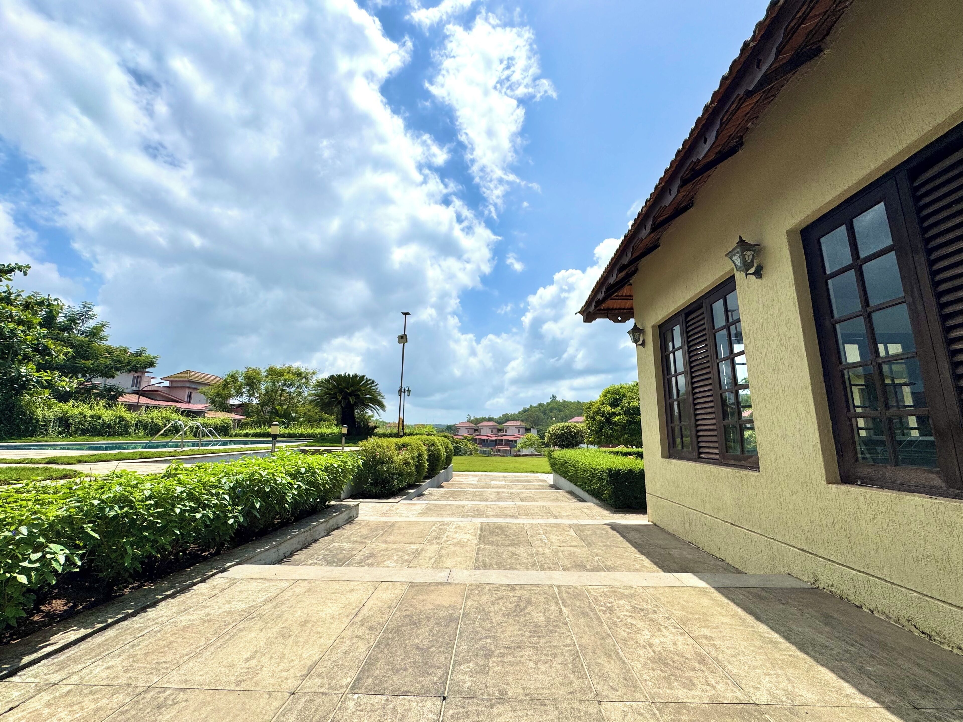 Un chemin pavé mène à un bâtiment doté d’un toit recouvert de tuiles et de grandes fenêtres.