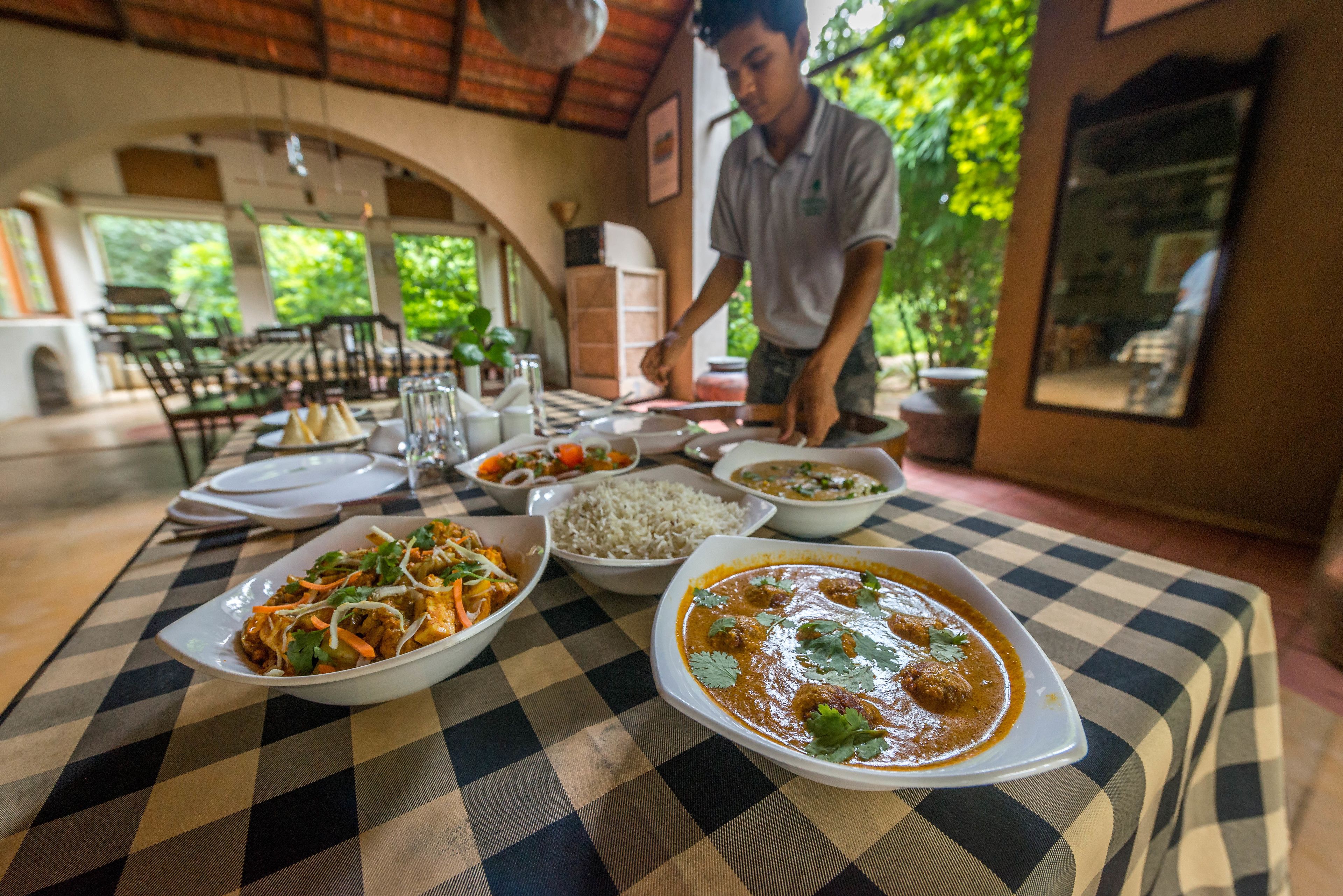 A dining table with various dishes, a waiter, and a checkered tablecloth.
