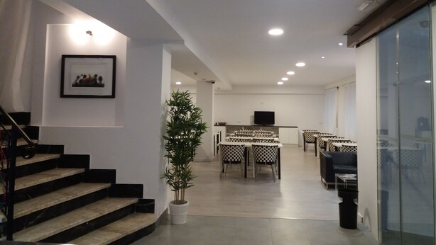 Un interior espacioso con una escalera, un comedor con sillas a cuadros y una planta en maceta.