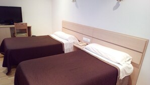 Habitación de hotel con dos camas individuales, un escritorio con computadora y una silla.