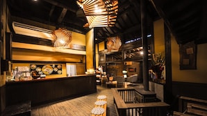 A restaurant interior with a wooden bar, seating area, and hanging wooden light fixtures. - Yamashinobu (Minamioguni)