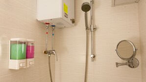 A bathroom with a shower, a hand dryer, and a mirror. - KG Garden Guest House (Kowloon)