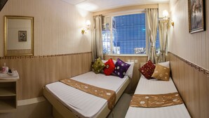 A hotel room with two beds, a bathroom, and a window with curtains. - KG Garden Guest House (Kowloon)