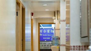 A hotel corridor with a sign indicating a guest house and Wi-Fi availability. - KG Garden Guest House (Kowloon)